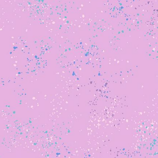 A flat-lay pattern swatch featuring a light pink background scattered with small blue, teal, and white speckles.